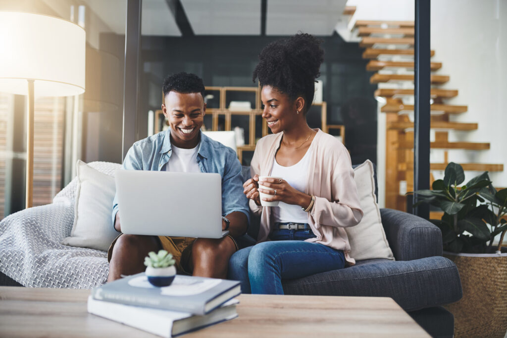 Shot of a happy young couple using a laptop together on the sofa at home