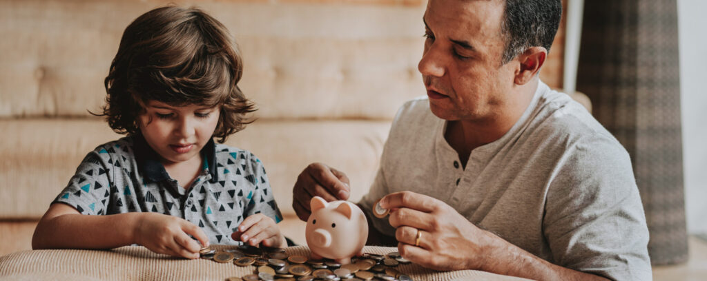 Child and adult organizing coins around a piggy bank.