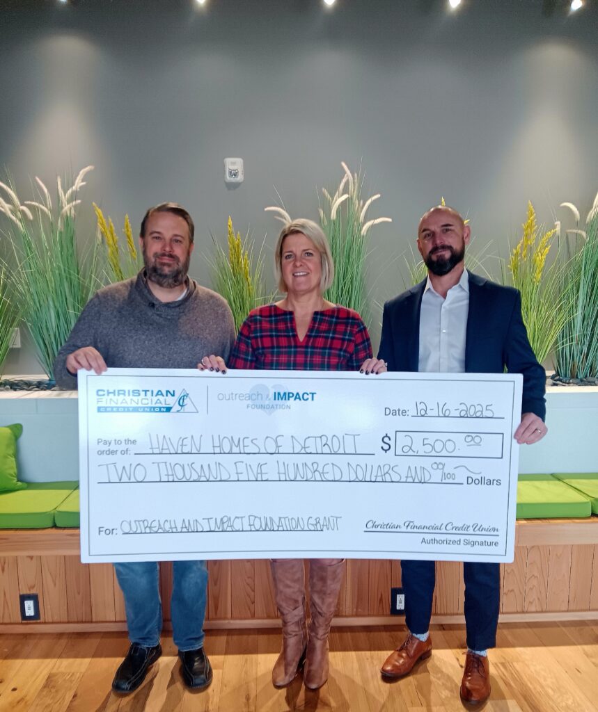 Three people standing indoors holding a ceremonial $2,500 grant check presented to Haven Homes of Detroit.
