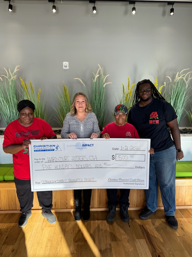 Four people hold a ceremonial $500 grant check for Hard Court Hitters CTA in a community gathering space.
