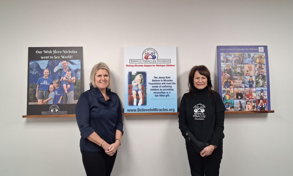 Individuals pose indoors near framed artwork and a donation presentation.