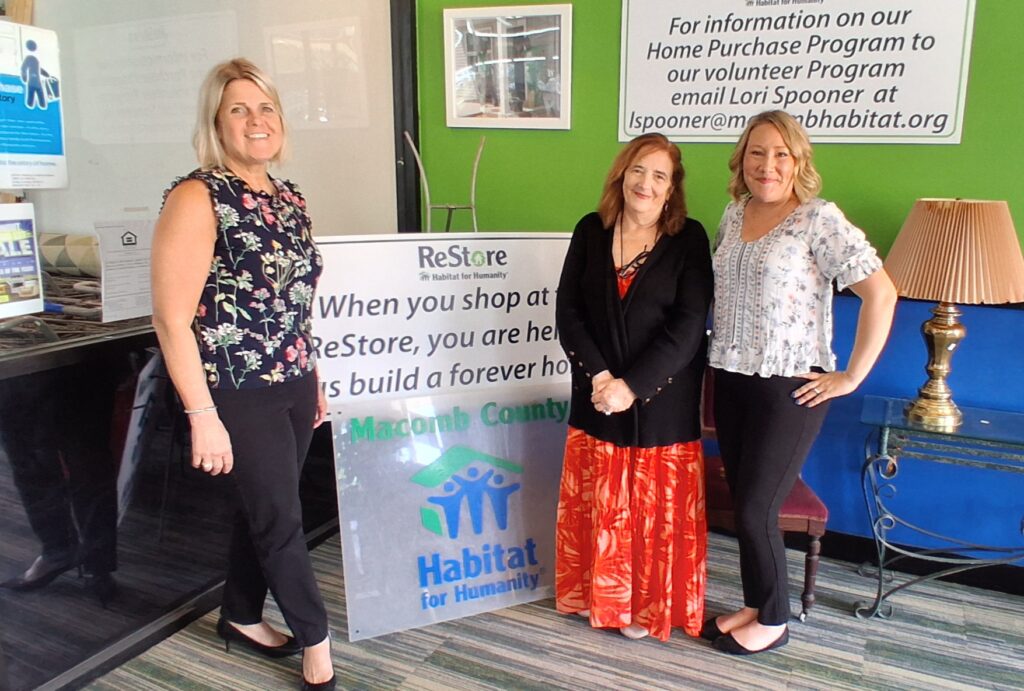 Representatives stand together inside a community space while displaying a donation check.