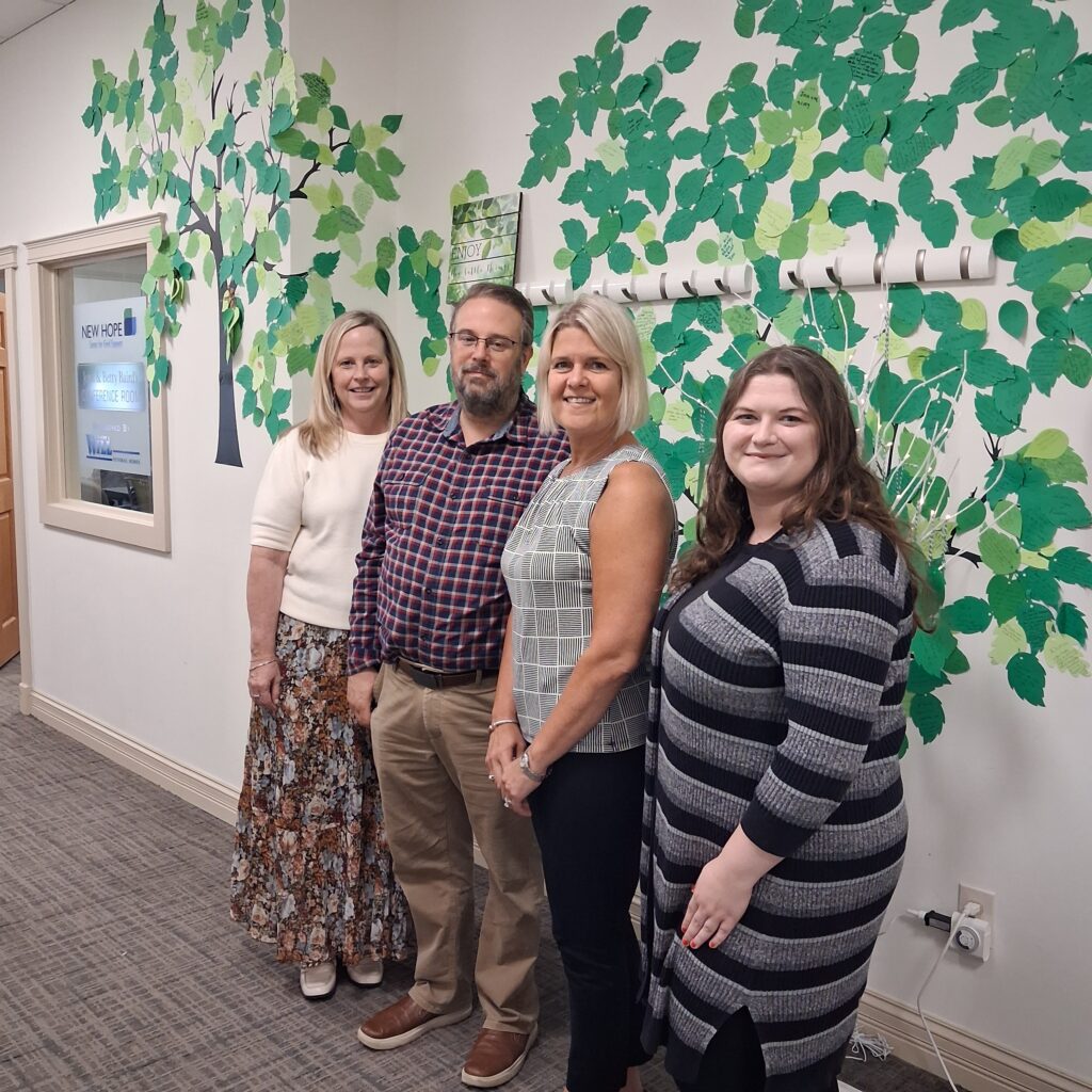 Several staff members stand together indoors in front of a decorative wall.